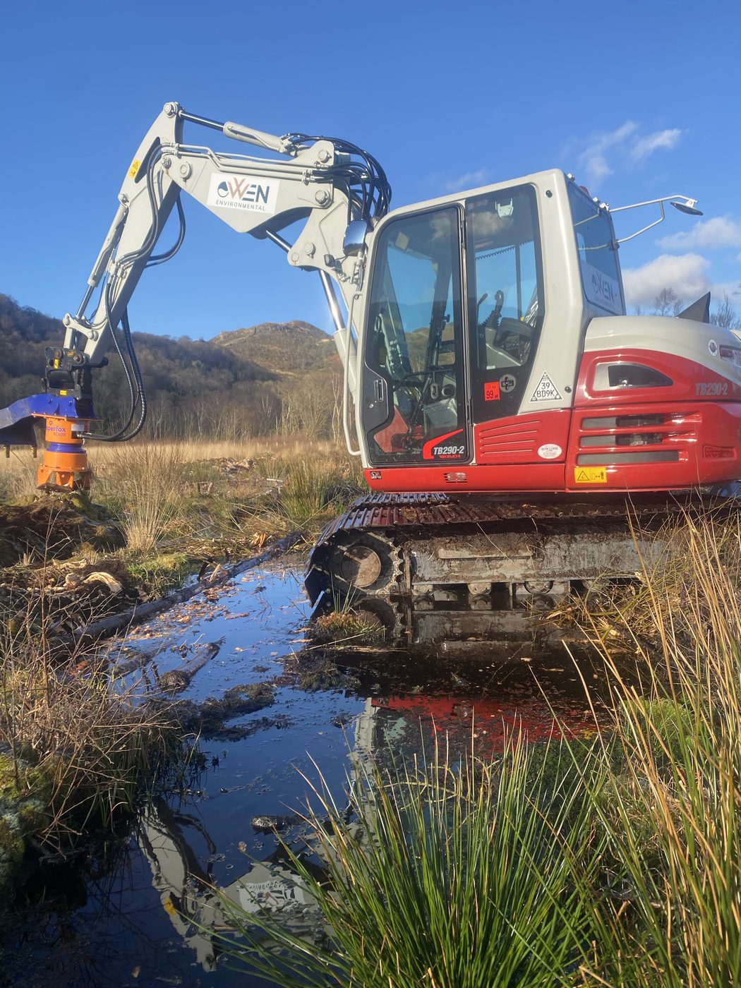 Water table restored — excavator standing over open water on rewetted bog